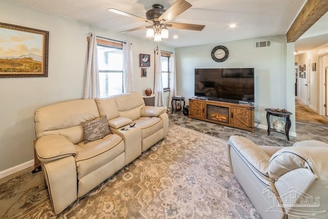 living room with baseboards, visible vents, and a ceiling fan