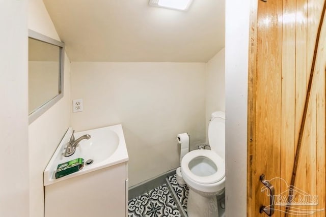 bathroom featuring tile patterned floors, toilet, vanity, and vaulted ceiling