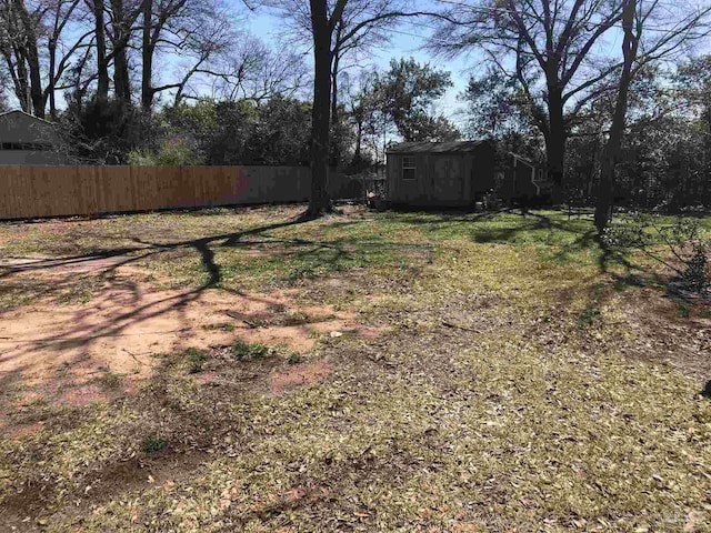 view of yard with an outbuilding, fence, and a shed