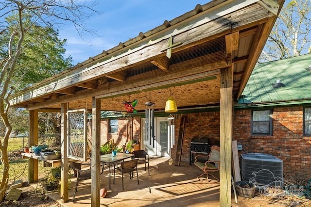 rear view of property with brick siding, metal roof, and central AC unit