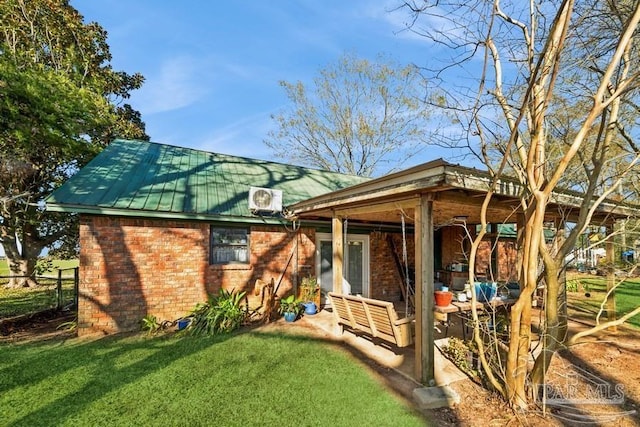 back of house with metal roof, brick siding, and a yard