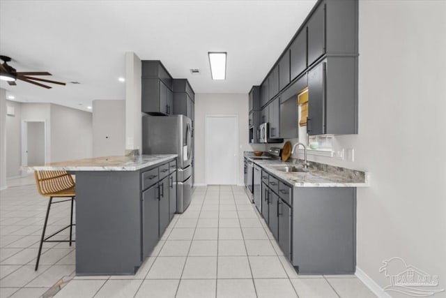 kitchen featuring light countertops, appliances with stainless steel finishes, a sink, a peninsula, and a kitchen breakfast bar