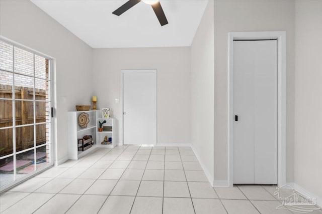 empty room with light tile patterned flooring, a ceiling fan, and baseboards