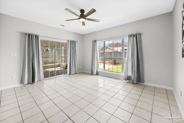 unfurnished room with light tile patterned floors, plenty of natural light, baseboards, and a ceiling fan