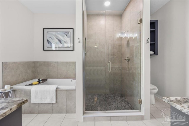 bathroom featuring tile patterned flooring, a shower stall, vanity, and toilet