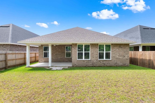 3826 Ranch Rd, Pace, FL 32571 - rear view of house featuring roof with shingles, a fenced backyard, brick siding, a patio area, and a yard