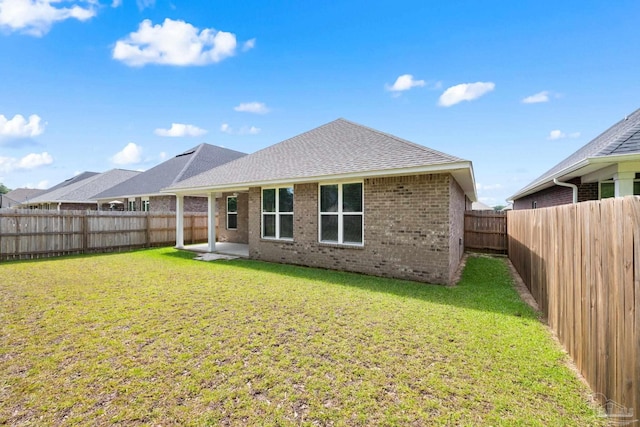 3826 Ranch Rd, Pace, FL 32571 - rear view of house with roof with shingles, a fenced backyard, brick siding, a patio area, and a lawn