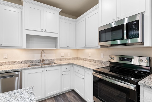 3826 Ranch Rd, Pace, FL 32571 - kitchen with dark wood finished floors, a sink, light stone countertops, appliances with stainless steel finishes, and white cabinetry