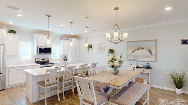 dining area with sink, crown molding, light hardwood / wood-style flooring, and a notable chandelier