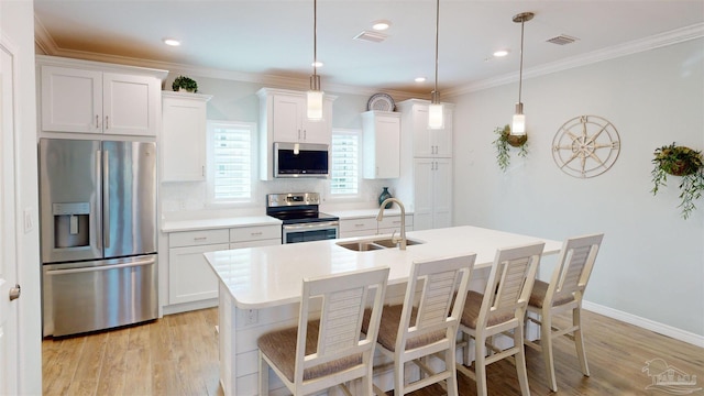 kitchen featuring sink, white cabinetry, decorative light fixtures, a center island with sink, and appliances with stainless steel finishes