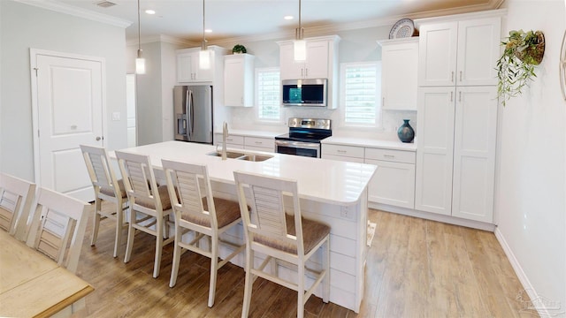 kitchen with appliances with stainless steel finishes, sink, white cabinets, and decorative light fixtures