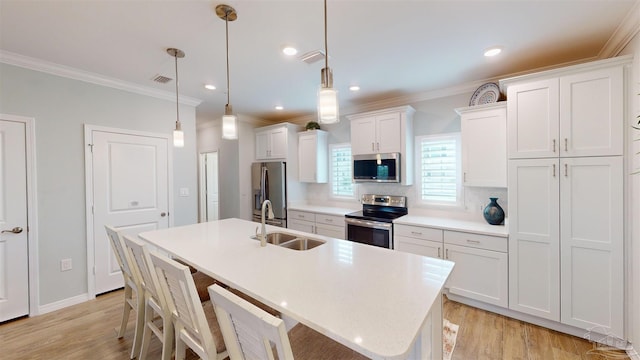 kitchen featuring sink, white cabinetry, hanging light fixtures, stainless steel appliances, and a center island with sink