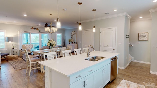 kitchen with sink, white cabinetry, decorative light fixtures, stainless steel dishwasher, and a kitchen island with sink