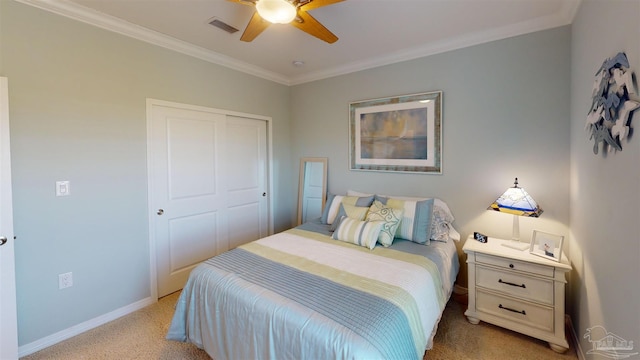 bedroom with crown molding, light colored carpet, ceiling fan, and a closet