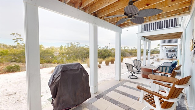 view of patio with grilling area, a water view, ceiling fan, and an outdoor fire pit