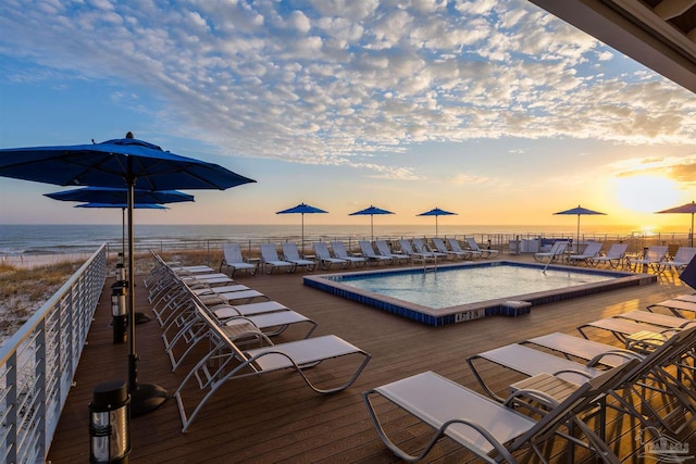 pool at dusk featuring a water view