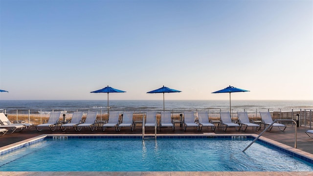 pool at dusk featuring a water view