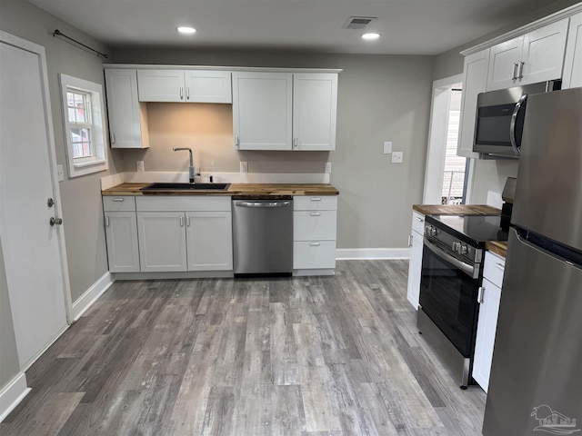 kitchen featuring white cabinetry, appliances with stainless steel finishes, sink, and wooden counters