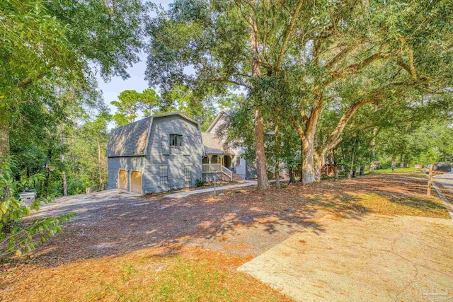 exterior space with driveway, a gambrel roof, a porch, and a garage