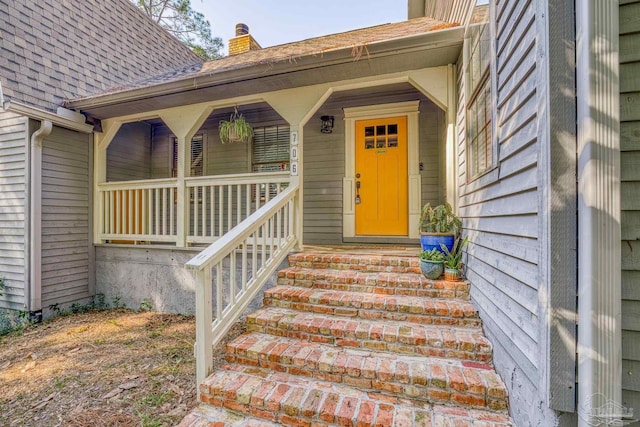 doorway to property with roof with shingles, a chimney, and a porch