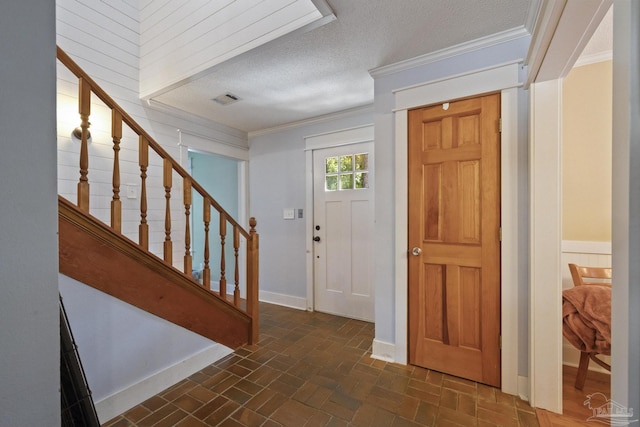 entrance foyer with crown molding, stairs, visible vents, a textured ceiling, and brick floor