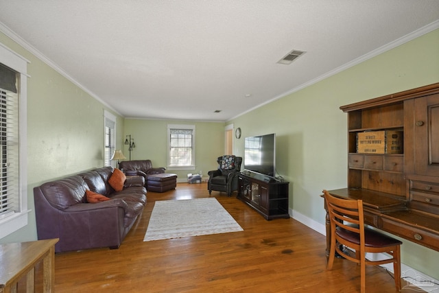 living area with crown molding, visible vents, wood finished floors, and baseboards