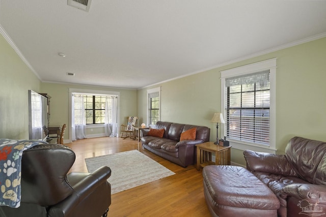 living area with visible vents, crown molding, and light wood-style flooring