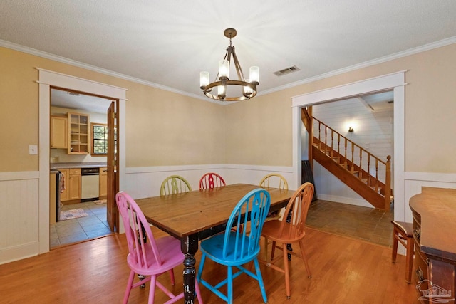 dining room with an inviting chandelier, crown molding, a textured ceiling, and light wood-type flooring