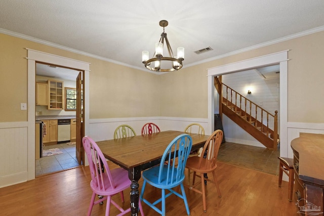dining area featuring visible vents, stairway, wainscoting, light wood-type flooring, and a notable chandelier