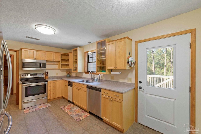 kitchen with light brown cabinets, hanging light fixtures, sink, appliances with stainless steel finishes, and a textured ceiling