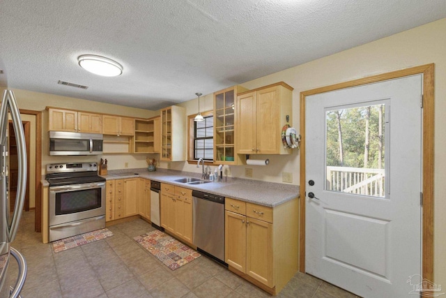 kitchen featuring a textured ceiling, a sink, visible vents, stainless steel appliances, and light brown cabinetry