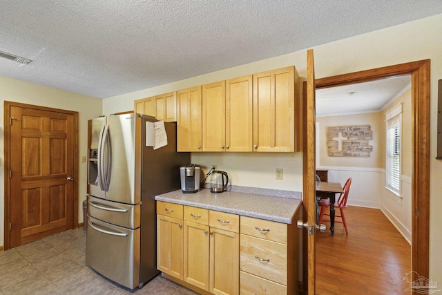 kitchen featuring light brown cabinets, stainless steel fridge, light countertops, visible vents, and a textured ceiling