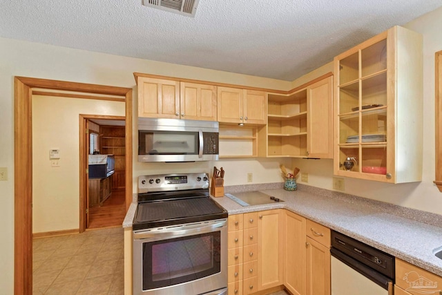 kitchen featuring a textured ceiling, light brown cabinets, and stainless steel appliances