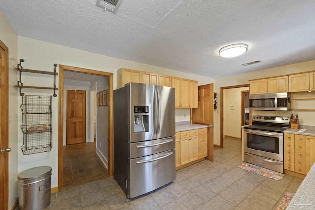 kitchen with light brown cabinetry, visible vents, appliances with stainless steel finishes, and light countertops