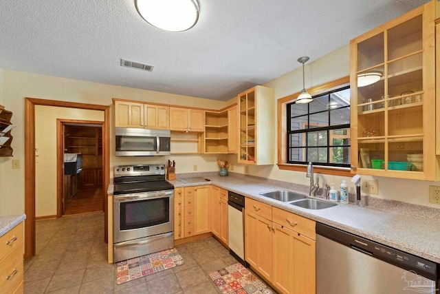 kitchen featuring light brown cabinetry, sink, appliances with stainless steel finishes, and decorative light fixtures