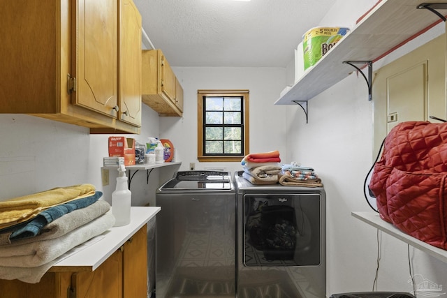 clothes washing area with a textured ceiling, washing machine and clothes dryer, and cabinet space