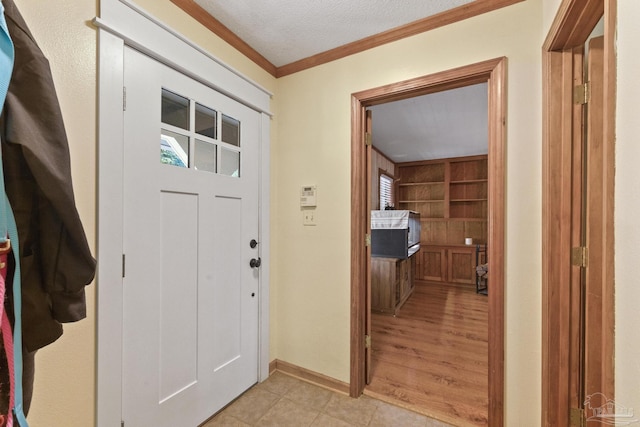 entrance foyer with light tile patterned floors, crown molding, a textured ceiling, and baseboards