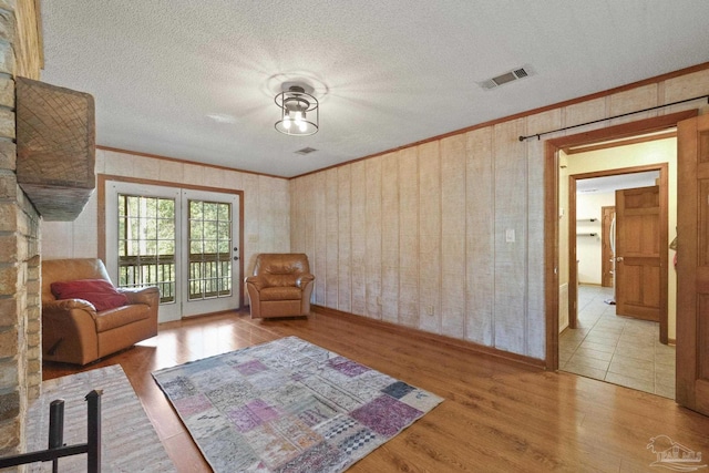 living area with ornamental molding and wood finished floors