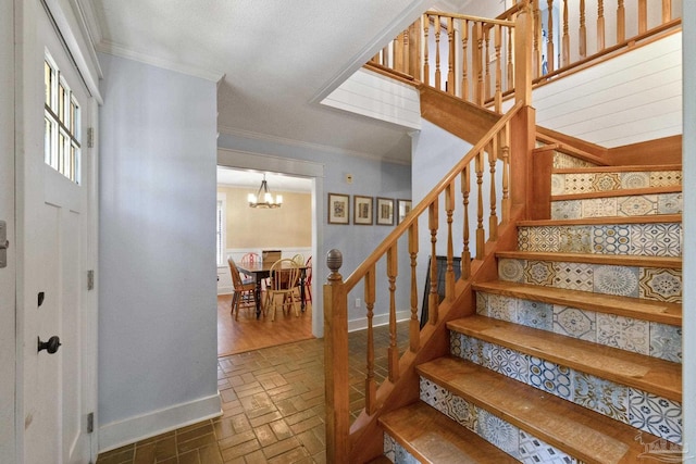 staircase featuring a chandelier, ornamental molding, brick floor, and baseboards