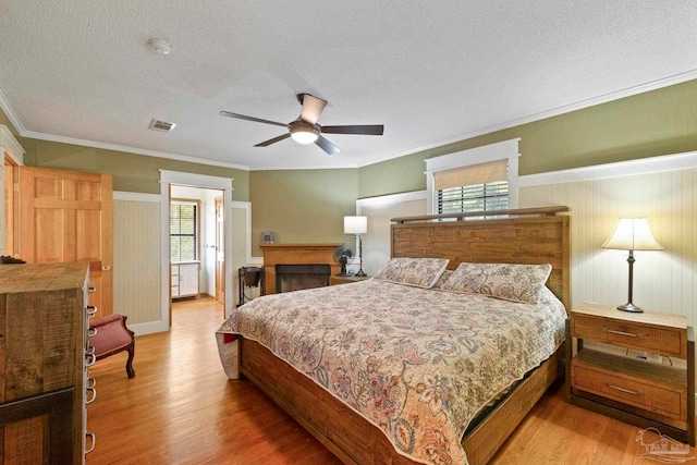 bedroom with crown molding, a textured ceiling, wood-type flooring, and ceiling fan