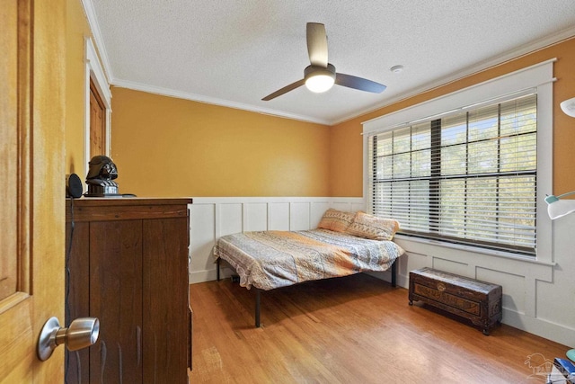 bedroom featuring a textured ceiling, wood finished floors, and crown molding