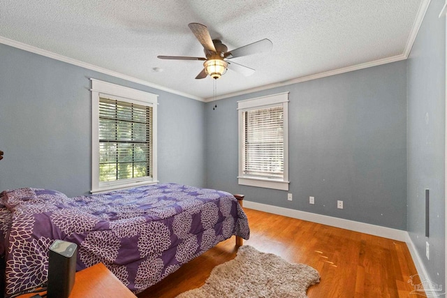 bedroom featuring ceiling fan, hardwood / wood-style flooring, a textured ceiling, and multiple windows