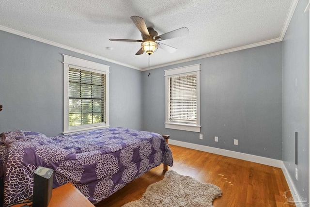 bedroom featuring baseboards, wood finished floors, a textured ceiling, and crown molding
