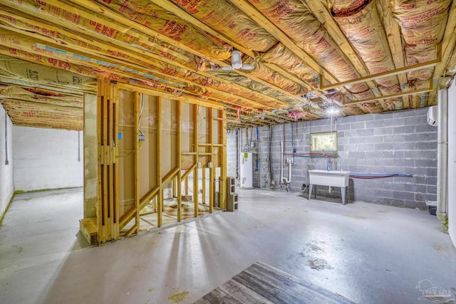 unfinished below grade area with concrete block wall, gas water heater, and a sink