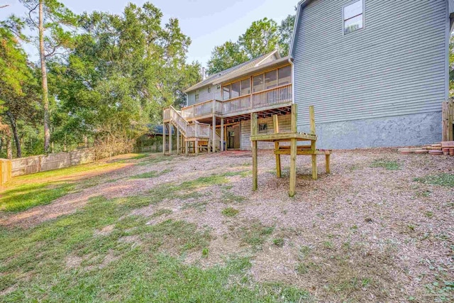 view of yard featuring a sunroom, a wooden deck, stairs, and fence