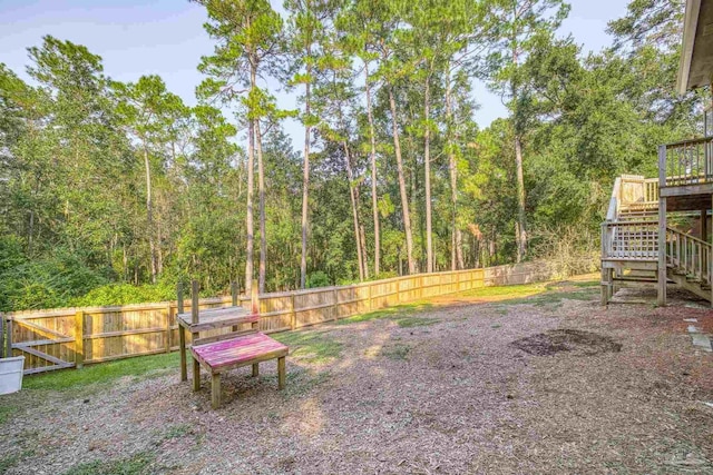 view of yard featuring a deck, stairway, and a fenced backyard