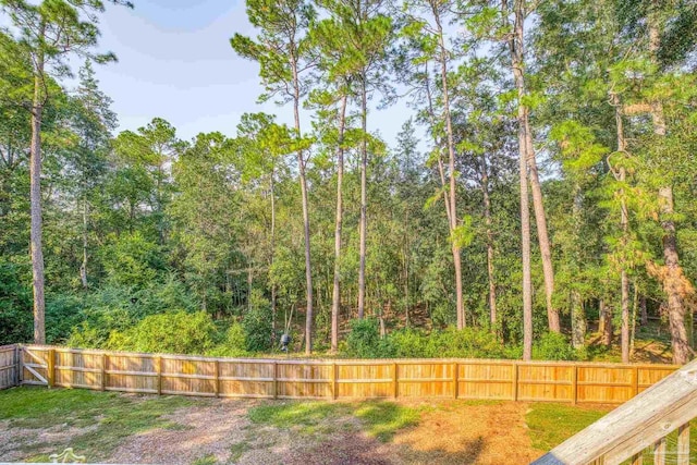 view of yard with a fenced backyard and a view of trees