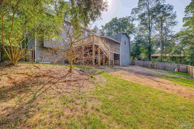 rear view of property with a fenced backyard, a wooden deck, a yard, and stairs