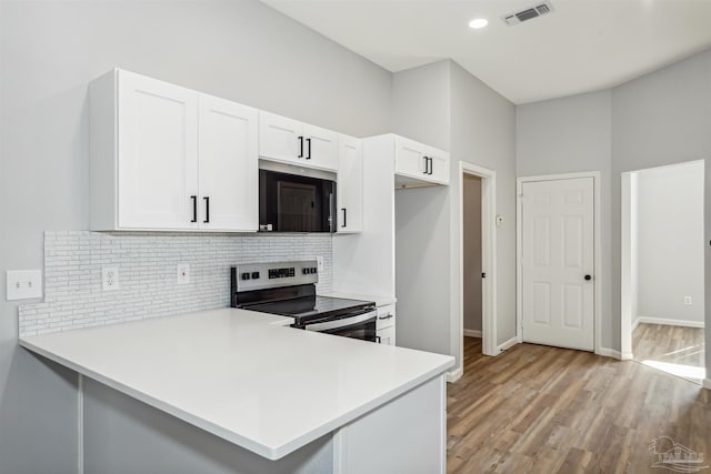 kitchen with light hardwood / wood-style floors, kitchen peninsula, backsplash, electric range, and white cabinetry