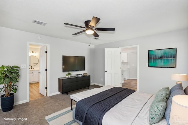 bedroom featuring light colored carpet, ceiling fan, and connected bathroom